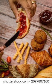 Breads. Buns With Jam. Hand Holding Slice Of Bread With Jam And Other Buns Blurred In The Background.