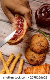 Breads. Buns With Jam. Hand Holding Slice Of Bread With Jam And Other Buns Blurred In The Background.