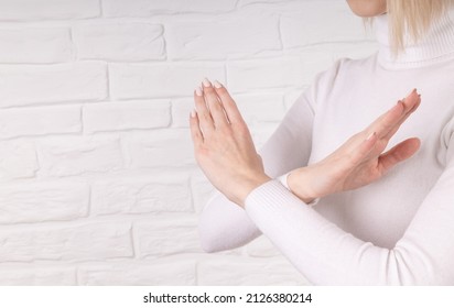 Break The Bias Symbol Of Woman's International Day. The Arms Of A Girl In White Are Crossed On A White Brick Wall. Woman Arms Crossed To Show Solidarity, Breaking Stereotypes, Inequality