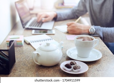 Break Time Concep. Closeup Cup Of Tea On Home Table. Worker Having Break,  Browsing Laptop With Cup Of Tea. 