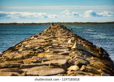 A break wall makes a fitting pier in which to fish from in Provincetown, Mass. along the Cape Cod National Seashore. on a sunny, summer day.