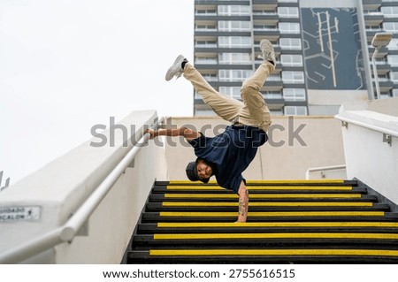 Breakdancer balances upside down on city stairs, showcasing agility and urban street style