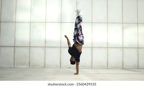 Breakdancer balancing on one hand performing a handstand freeze in urban environment - Powered by Shutterstock