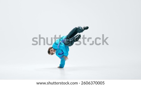 Breakdancer spinning low, hand stabilizing movement, legs suspended, core engaged in perfect motion. Concept of freestyle, musicality, dance energy, street culture, power, precision in action.