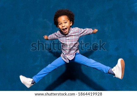 Breakdancing joyful african american cute little child boy levitating in jump. Funny small excited dancing kid having fun hop. Positive emotions and triumph concept.