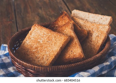 Breakfast background, white bread toasts in wicker breadbasket on checkered table napkin half covering wooden table, closeup - Shutterstock ID 683404516