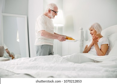 Breakfast to bed. Delighted nice aged man bringing breakfast to his wife while caring about her - Powered by Shutterstock