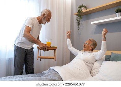 Breakfast in bed. Senior man bringing breakfast to his wife in bedroom. - Powered by Shutterstock