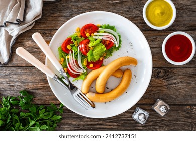 Breakfast - boiled sausages and fresh vegetables served on wooden table - Powered by Shutterstock