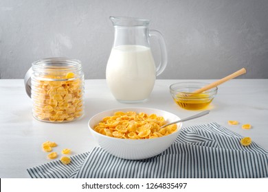 Breakfast with bowl of cornflakes, honey and milk jug on light table. Morning healthy food - Powered by Shutterstock