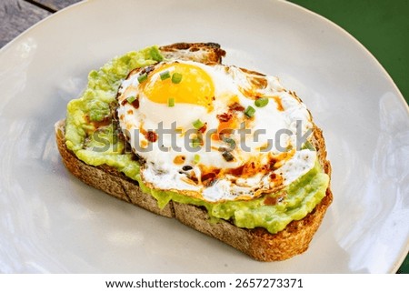 breakfast bread filled with crushed avocado and egg on top on a white plate