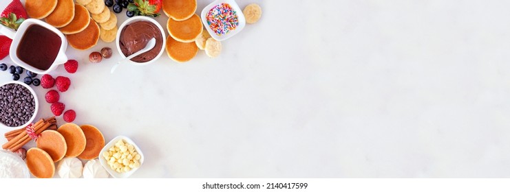 Breakfast Or Brunch Pancake Buffet Corner Border. Overhead View On A White Marble Banner Background. Mini Pancakes With Assorted Toppings.