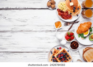 Breakfast or brunch side border on a white wood background. Top down view. Variety of sweet and savory food items.