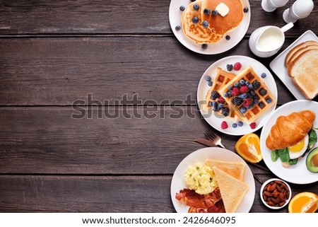 Breakfast or brunch side border on a dark wood background. Above view. Selection of sweet and savory food items.