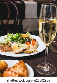 Breakfast Or Brunch With Sparkling Wine In A Fancy Hotel Or Restaurant. Crepes With Caviar, Greens And Other Food. Mini Pies And Variety Of Crepes On A Background.