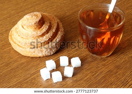Breakfast of a bun, sugar and tea on a wooden table. Axonometric view.