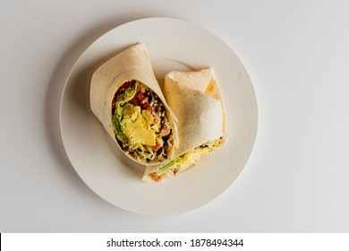 Breakfast burrito. Bacon, eggs, onions, peppers sautéed and wrapped a flour tortilla. Served with salsa, potato hash, blueberries and blackberries. Classic breakfast or brunch menu favorite. 