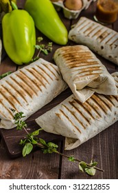 Breakfast Burrito On Wood Board And Wood Table, Eggs, Pepper, Potatoes And Meat Inside