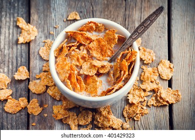 Breakfast Cereal Wheat Flakes In Bowl With Milk On Wooden Table