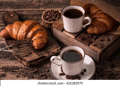 Breakfast with coffee and croissants on wooden vintage table