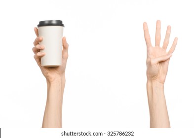 Breakfast And Coffee Theme: Man's Hand Holding White Empty Paper Coffee Cup With A Brown Plastic Cap Isolated On A White Background In The Studio, Advertising Coffee 