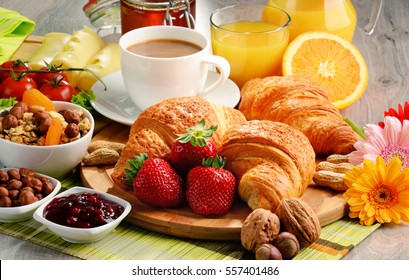 Breakfast consisting of croissants, coffee, fruits, orange juice and jam. Balanced diet.