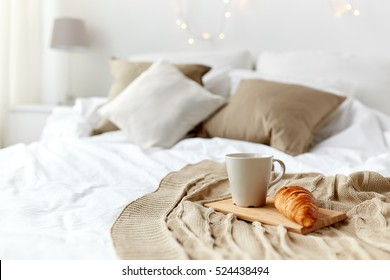 Breakfast, Coziness, Morning, Holidays And Winter Concept - Cozy Bedroom With Coffee Cup And Croissant On Wooden Board In Bed At Home