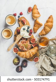 Breakfast With Croissants, Homemade Ricotta Cheese, Figs, Fresh Berries, Prosciutto Meat, Honey And Espresso Coffee On Rustic Serving Board Over White Marble Background, Top View, Vertical Composition