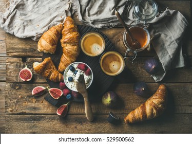 Breakfast With Croissants, Homemade Ricotta Cheese, Figs, Fresh Berries, Honey And Espresso Coffee On Dark Serving Board Over Rustic Wooden Background, Top View, Horizontal Composition