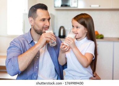 Breakfast With Dad. Father And Little Daughter Drinking Milk Sitting In Kitchen At Home