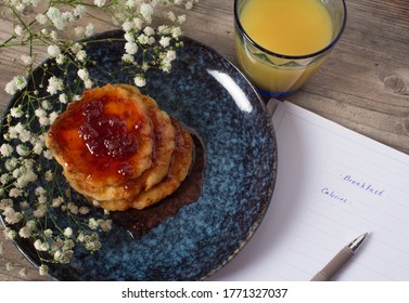 Breakfast With Flowers. Pancakes With Strawberry Jam. Notepad To Write Calories. Dieting And Calorie Control For Wellness. Woman Calculate Calories Of Food During Dieting For Lose Weight Program