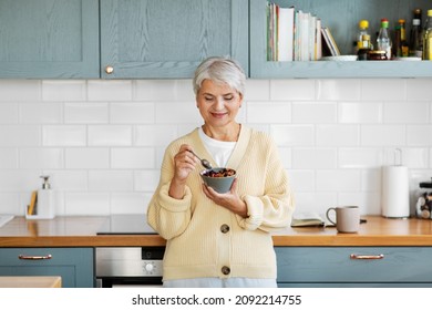 breakfast, food and people concept - happy smiling woman with spoon eating cereal on kitchen at home - Powered by Shutterstock