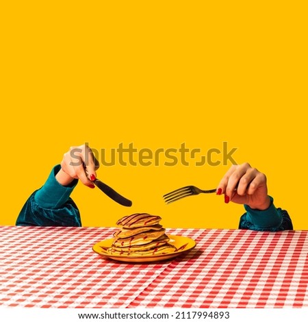 Breakfast. Food pop art photography. Female hand and sweet pancakes on plaid tablecloth isolated on bright yellow background. Vintage, retro 80s, 70s style. Complementary colors, Copy space for ad