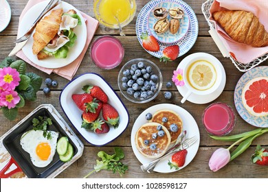 Breakfast food table. Festive brunch set, meal variety with fried egg, pancakes, croissants, smoothie ,fresh berries and fruits. Overhead view