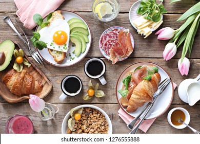 Breakfast Food Table. Festive Brunch Set, Meal Variety With Fried Egg, Croissant Sandwich, Granola And Smoothie. Overhead View