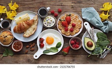 Breakfast food table. Festive brunch set, meal variety with  fried egg, croissant sandwich, cheese, avocado and desserts. Overhead view - Powered by Shutterstock