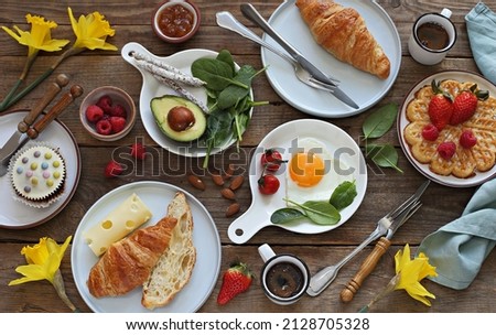 Breakfast food table. Festive brunch set, meal variety with  fried egg, croissant sandwich, cheese, avocado and desserts. Overhead view