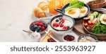 Breakfast food table. Huge healthy breakfast spread on a table with orange juice, fruit, vegetable, muesli, salmon, egg and croissants on a light background. Top view. Panorama with copy space.