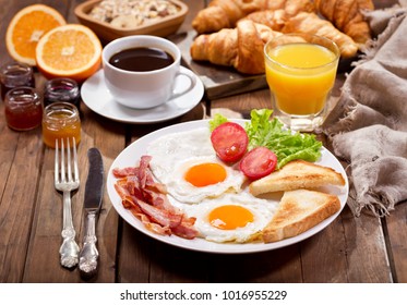 breakfast with fried eggs, coffee, juice and fresh fruits on wooden table