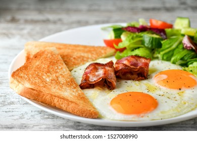 Breakfast. Fried eggs, toasts, bacon and salad. Healthy food