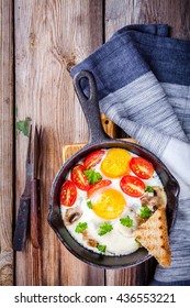 breakfast: fried eggs with tomatoes and mushrooms in pan