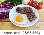 Breakfast with goetta  and fried egg on plate (Cincinnati Breakfast Classic) on wooden table