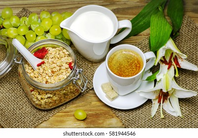 Breakfast with granola,warm milk,fresh bunch of grapes and a cup of espresso placed with beautiful lilies flower on wooden background.