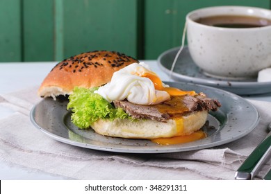 Breakfast With Homemade Sandwich With Baked Meat And Soft-boiled Egg And Cup Of Hot Pocket Tea Over White Wooden Table With Turquoise Wall At Background. 