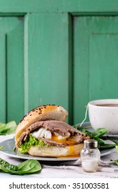 Breakfast With Homemade Sandwich With Baked Meat And Soft-boiled Egg, Spinach Salad And Cup Of Hot Pocket Tea Over White Wooden Table With Turquoise Wall At Background. 