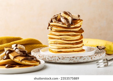 Breakfast with homemade stack of pancakes with chocolate spread, syrop and sliced banana served on white table. - Powered by Shutterstock