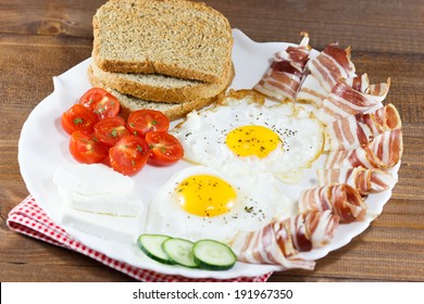 Breakfast including  bread, eggs, bacon, cheese, tomato