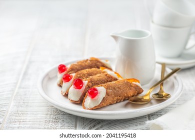 Breakfast with Italian pastry cannoli with ricotta cheese cream topped with cherries. Coffee cups on background. White wood surface. Copy space.