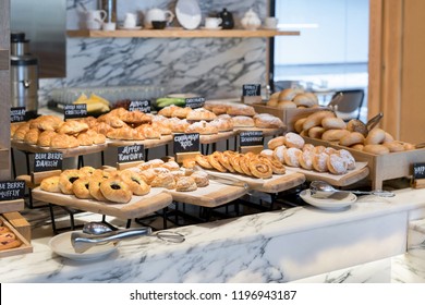 Breakfast lines of different flavor danishs, buns and muffins in wooden trays at the hotel restaurant