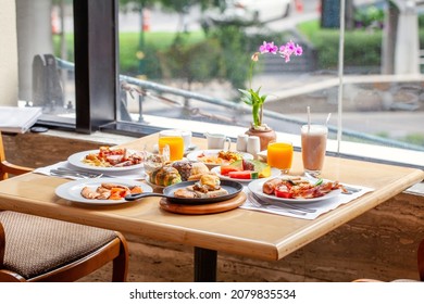 Breakfast In Luxury Hotel. Table Full Of Various Food From Buffet In Modern City Resort. Morning Food - Fresh Bakery, Glasses Of Orange Juice, Eggs And Plate With Tropical Fruits In Restaurant